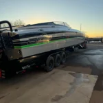 Custom high-performance DCB boat on trailer at sunset, showcasing sleek design and vibrant green accents.