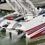 Custom high-performance DCB boat with sleek design, featuring distinctive red and blue accents, launching on water, showcasing luxury craftsmanship and engineering.