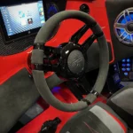 Custom boat interior featuring a sleek steering wheel, high-tech display, and luxurious red accents, reflecting DCB Performance Marine's commitment to hand-crafted luxury and advanced engineering.