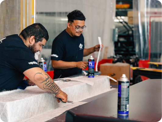 Two workers preparing composite materials for boat manufacturing, demonstrating craftsmanship in the build process at DCB Performance Marine.