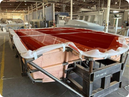 Composite boat hull structure in manufacturing facility, showcasing bulkheads and bond line preparation, reflecting DCB Performance Marine's custom boat build process.