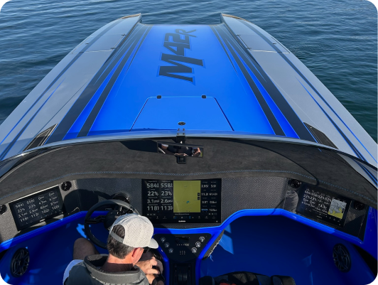 Top view of a high-performance boat cockpit featuring a blue and black design, with a driver at the helm, digital displays showing navigation and performance metrics, and a sleek, modern aesthetic.