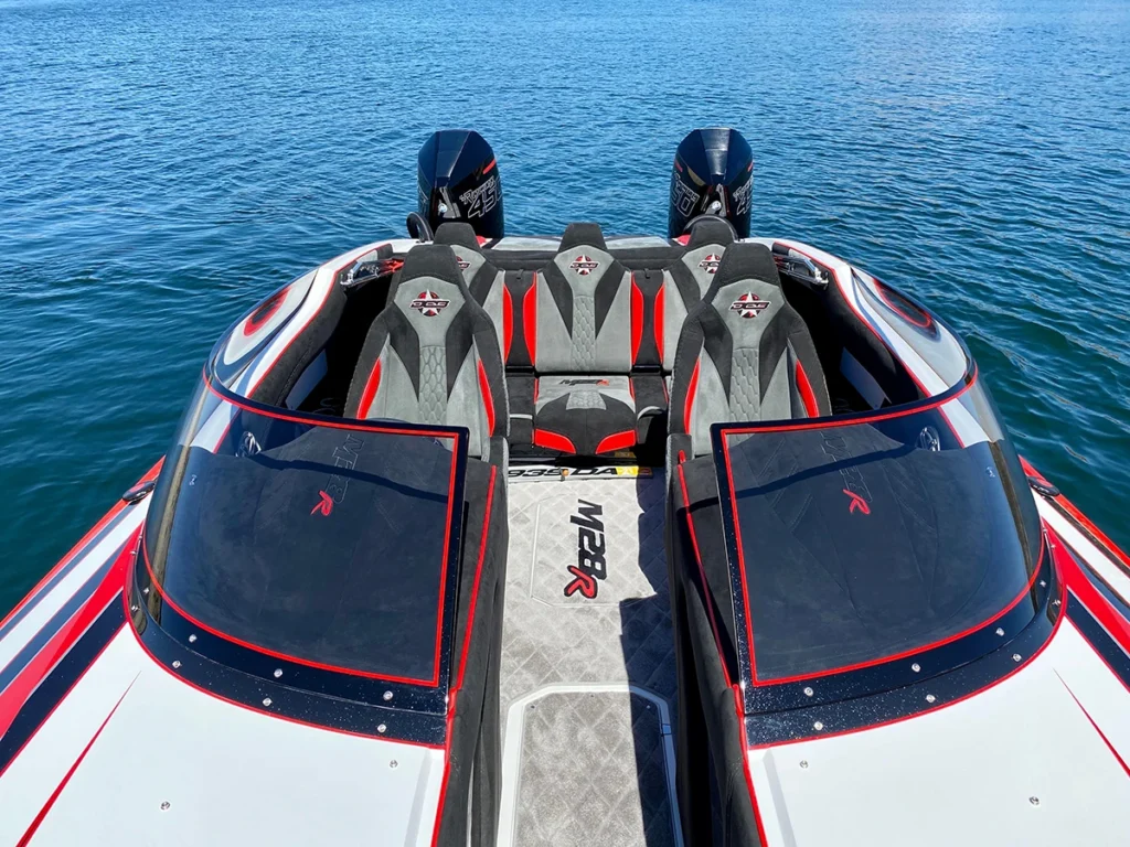 DCB M28R walkthrough open bow boat interior with sleek seating and dual outboard motors, set against a tranquil water backdrop.