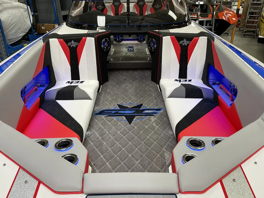 M31 model interior featuring custom upholstery in red, white, and black, with seating for six, illuminated accents, and a branded floor design, showcasing the boat's sleek and family-friendly layout.