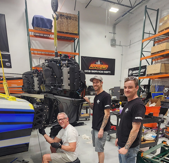 Three skilled technicians working on the engine installation in the DCB Performance Marine service department, showcasing attention to detail and quality craftsmanship in the boat manufacturing process.