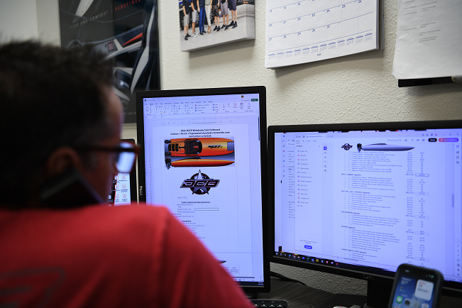 Person reviewing detailed build specifications for a DCB Performance Marine boat on dual monitors, showcasing custom options and performance features.