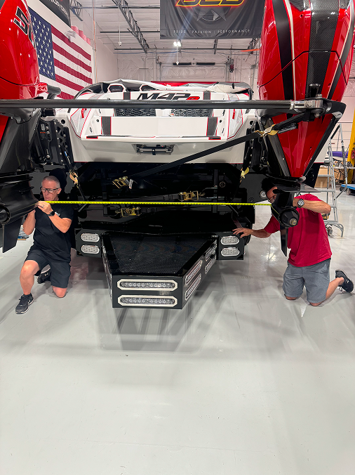 Technicians measuring the fitment of a DCB Performance Marine boat on a trailer, showcasing meticulous attention to detail in the assembly process.